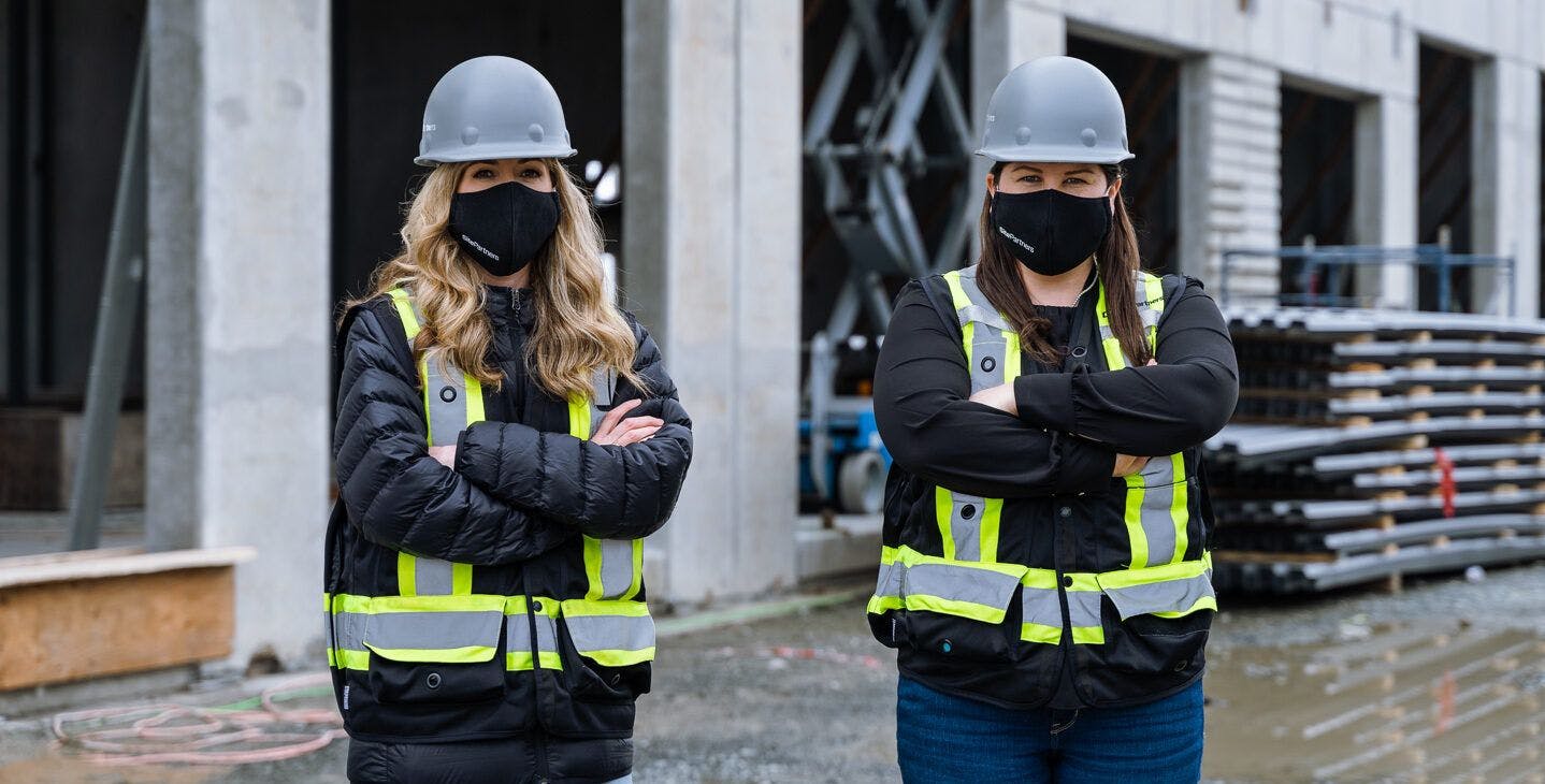 Two women in masks on a job site