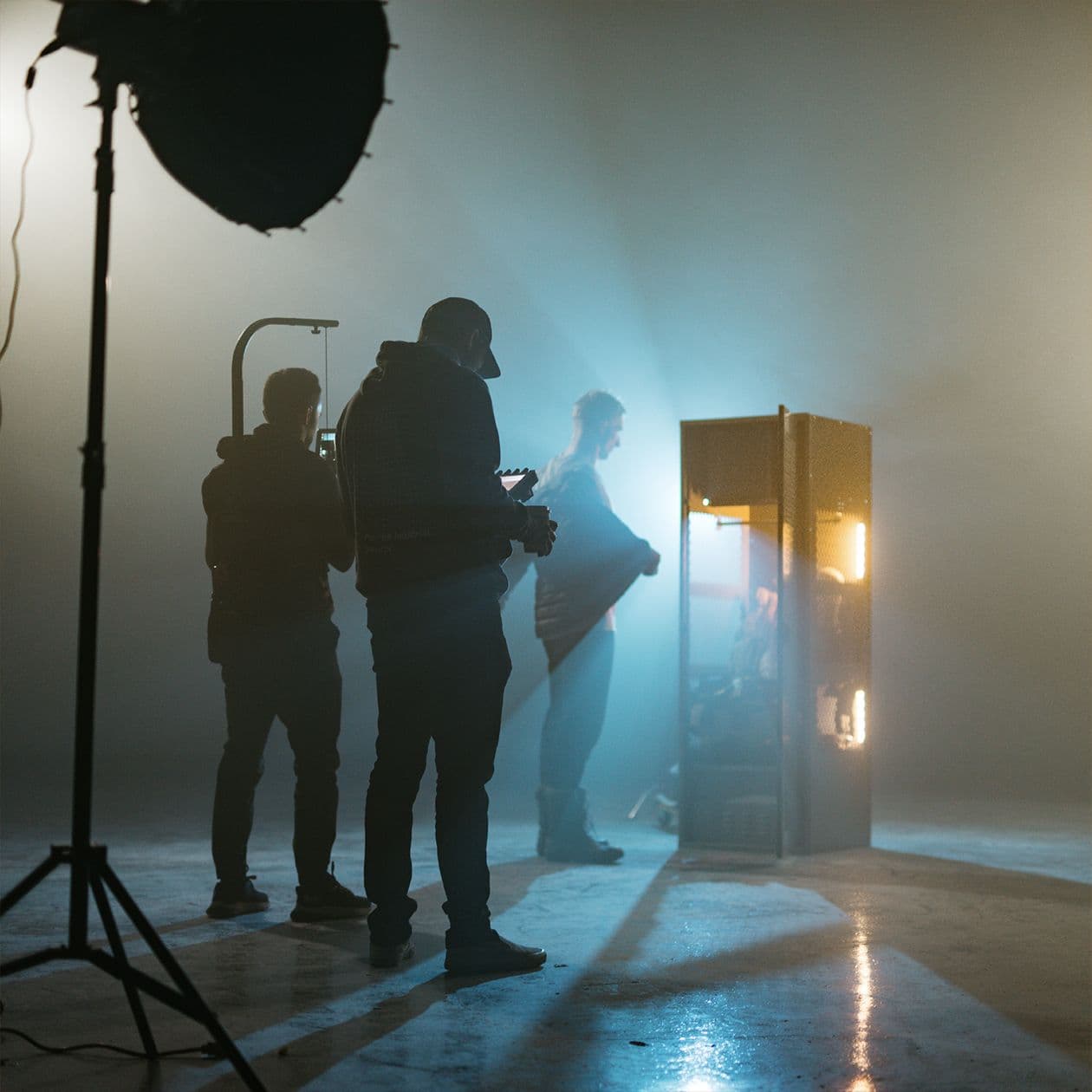 Video team filming firefighter near locker in a smokey void.